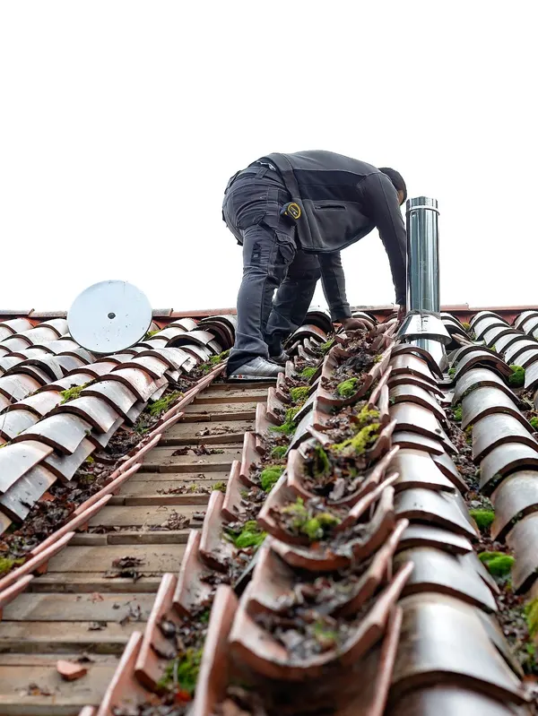 Artisan en intervention sur une toiture en tuiles canal