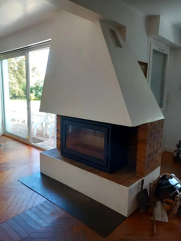 Insert posé dans une cheminée à hotte blanche, parquet en point de Hongrie
