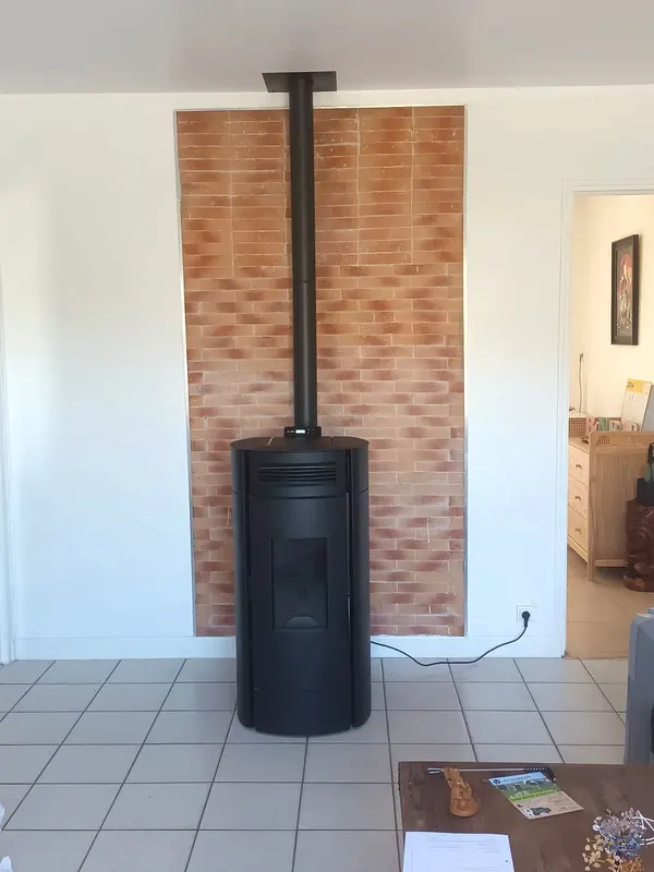 Poêle noir devant un habillage mural en briquettes