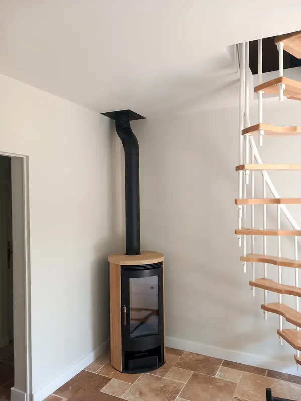 Poêle habillé de bois clair au pied d’un escalier hélicoïdal